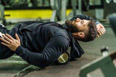 Spor adamı Kas ve Fasya için siyah köpük tekerlekli paten kullanıyor - Erkek sporcu spor salonundaki antrenmandan sonra ağrılı kasları rahatlatıyor - sağlık ve spor vücut bakımı konsepti