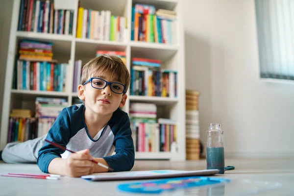 4歳の小さな白人少年は カメラのコピースペースを探して水彩や絵筆を使用して自宅の絵画で床に横たわっています — ストック写真