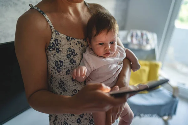 3ヶ月の赤ちゃんを持つ大人の女性の母親は 自宅でインターネットの閲覧やソーシャルネットワークのテキストメッセージのための携帯電話を使用している間家庭内生活の母親と子育て忙しい概念 — ストック写真