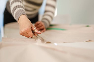 Bilinmeyen beyaz kadının elinde makas, evinde ya da stüdyosunda tekstil kesen ellerine yaklaş. Hobi ve terzilik konsepti fotokopi alanı.