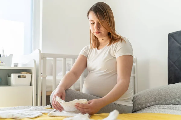 Vooraanzicht Van Gelukkige Blanke Vrouw Zittend Bed Met Babykleertjes Bij — Stockfoto