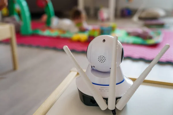 Baby monitor surveillance camera watching 5 months old child playing alone at home