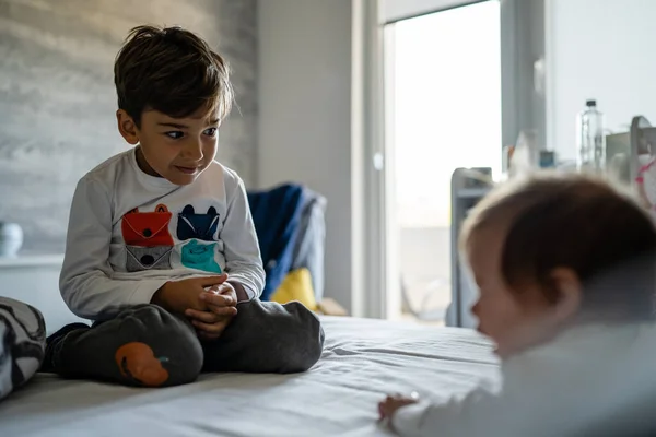 Küçük Beyaz Bir Çocuk Kardeşiyle Ilgilenirken Evde Kardeşlik Içinde Yatakta — Stok fotoğraf