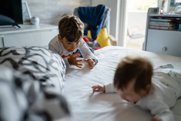 小さいCaucasian男の子世話をしながら彼の赤ちゃんの弟や妹の家でベッドの上で再生日同胞団と家族の成長の概念 — ストック写真