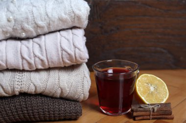 Bir demet kırmızı çay ve bir demet tarçın ve ahşap bir arka planda yarım limon kış yünlü kazakların yanında. Sağlıklı içki ve kış konsepti