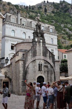 Kotor, Karadağ - 20 Temmuz 2021 St. Luka Kilisesi, Kotor 'da turistlerle. Kilisenin kubbesi ve çan kulesi dağın arka planına karşı