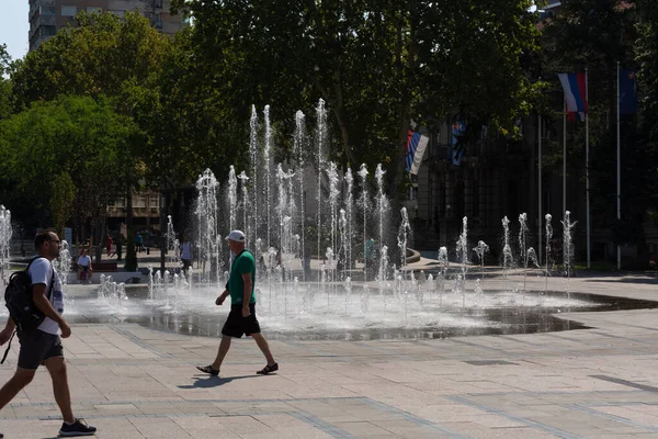 Niş, Sırbistan - 14 Ağustos 2021 Nis şehrindeki modern çeşme ve sıcak bir yaz gününde şehir meydanında yürüyen insanlar