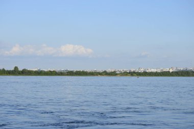 Büyük şehrin, ağaçların ve büyük nehrin üzerindeki bulutlu mavi gökyüzünün manzarası..