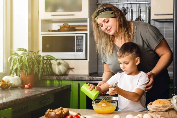 Caring mother help little preschooler son prepare cookies, smiling loving mom learn cooking with small boy child, making lunch on weekend in kitchen together