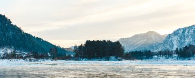 Nehirde kayalar, taşlar ve buzla kaplı kış manzarası. Ağaçlar ve taşlar karla kaplı.