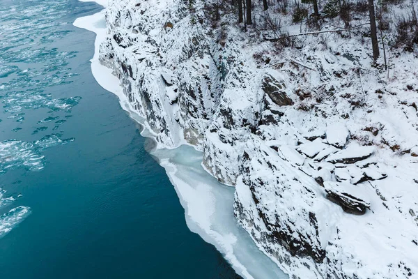 Vue sur les rochers, les pierres et la glace dans la rivière en hiver. Les arbres et les pierres sont couverts de neige — Photo