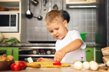 Kapalı alanda faaliyet: mutfakta yemek pişiren genç pozitif çocuk. Kurabiye yap