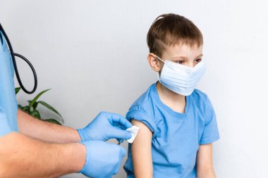 Aşı konsepti. Erkek doktor klinikte küçük şirin bir çocuğu aşılıyor, yakın plan. Coronavirus Covid-19 'a karşı aşı oturumu ve dokunulmazlık geliştirme