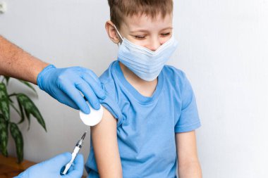 Aşı konsepti. Erkek doktor klinikte küçük şirin bir çocuğu aşılıyor, yakın plan. Coronavirus Covid-19 'a karşı aşı oturumu ve dokunulmazlık geliştirme