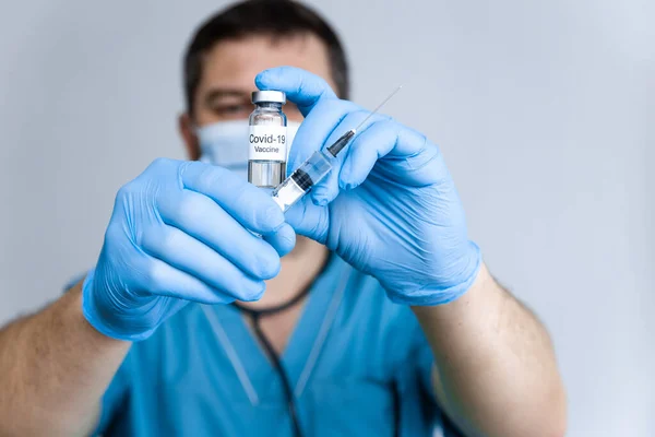 Médico en guantes de goma que sostiene la vacuna COVID-19 contra el coronavirus en vial y jeringa. Salud y concepto médico. De cerca. — Foto de Stock