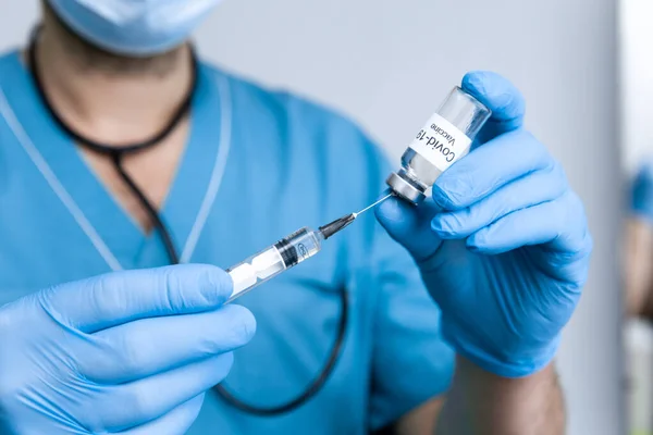 Mavi ameliyat eldivenli bir doktor dünya çapında bir salgın olan Coronavirus covid-19 'a karşı aşı yapmak için bir koronavirüs aşısını şırıngaya çeviriyor. Sağlık ve Tıp Konsepti