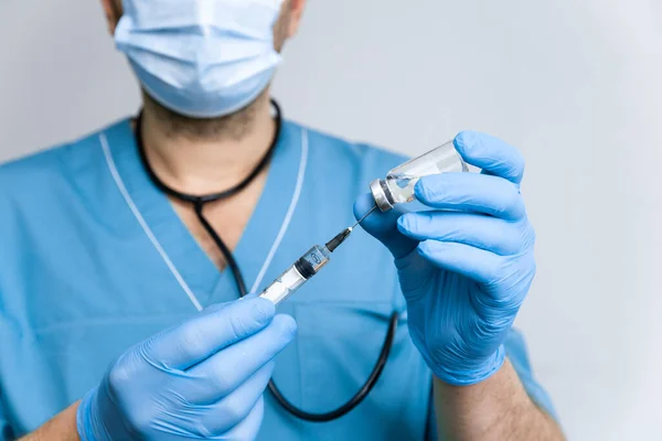 El médico con guantes quirúrgicos azules marca una vacuna contra el coronavirus en una jeringa para vacunar contra un coronavirus epidémico mundial covid-19. Salud y concepto médico — Foto de Stock