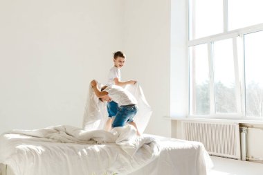 Kapalı alanda pozitif aktivite. Küçük çocuklar yatakta zıplıyor ve gün ışığında yastıklarla kavga ederek eğleniyorlar. Günaydın.