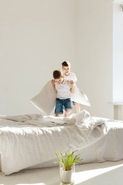 Kapalı alanda pozitif aktivite. Küçük çocuklar yatakta zıplıyor ve gün ışığında yastıklarla kavga ederek eğleniyorlar. Günaydın.