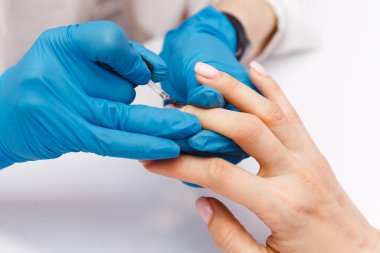 Kadın manikürcü, güzellik salonundaki müşterinin tırnaklarını ojeyle kaplıyor. Manikür, güzellik prosedürleri ve kişisel bakım. Yakın çekim elleri görünümü