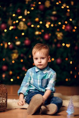 İçeride yeni yıl aktivitesi. Hediyeler ve mandalinalarla Noel ağacının yanında Mutlu Genç Bebek
