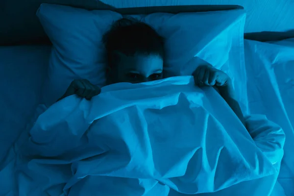 Kisfiú Fekszik Ágyban Sötét Éjszakában Fél Rémálmoktól Szörnyű Gyermeki Álmoktól Stock Fotó