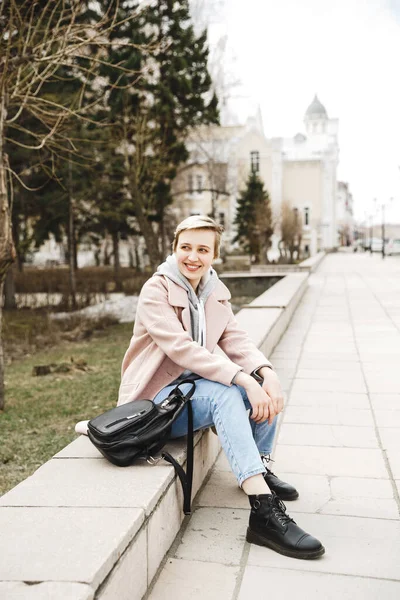 Attractive hipster blonde girl in a pink coat walks around beautiful authentic old town. The concept of freedom. creativity and inspiration — стоковое фото