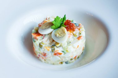 Beyaz bir tabakta bezelye filizleriyle süslenmiş Olivier salatası. Geleneksel Yeni Yıl ve Noel Rus salatası. Yakın plan, seçici odaklanma, beyaz arka plan. Bak Les.