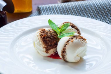 Nane yaprağıyla beyaz bir tabakta üç top dondurma..