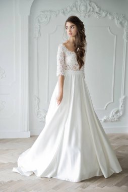 Güzel makyajlı, saç stili ve stüdyo fotoğraflı şık bir gelinlik giymiş genç bir gelinin portresi. Genç, çekici bir model.