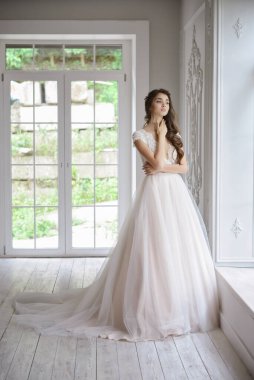 Portrait of a young bride in a fashionable wedding dress with beautiful makeup and hairstyle, studio photo indoors. Young, attractive model clipart