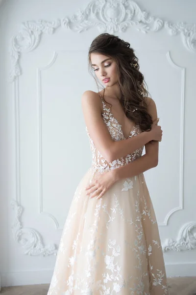 Portrait of a young bride in a fashionable wedding dress with beautiful makeup and hairstyle, studio photo indoors. Young, attractive model