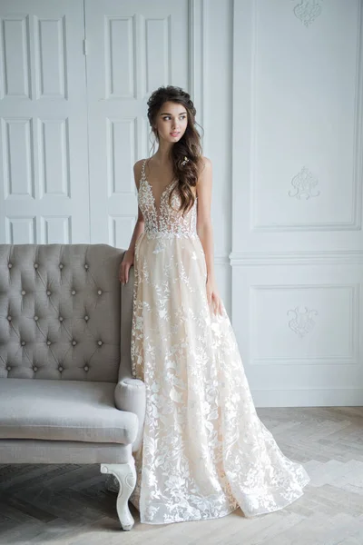 Portrait of a young bride in a fashionable wedding dress with beautiful makeup and hairstyle, studio photo indoors. Young, attractive model