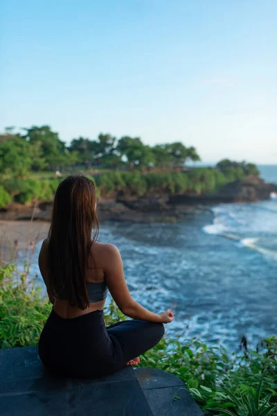 Young woman practicing yoga near the sea. Harmony, meditation and travel concept. Healthy lifestyle