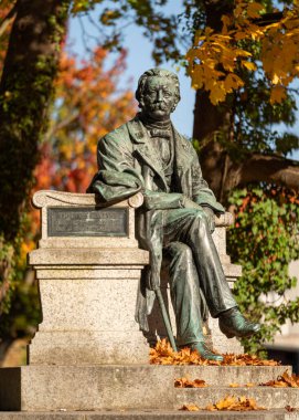 Neuruppin, Almanya - 18 Ekim 2025: Yazar Theodor Fontane 'in Neuruppin, Almanya' da 18 Ekim 2025 tarihinde renkli yapraklı ağaçlara karşı anıtı