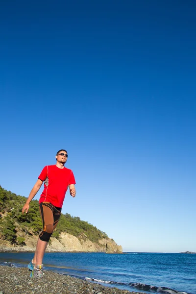 Berglauf. Mann läuft bei Sonnenuntergang auf einer Landstraße in den Bergen — Stockfoto