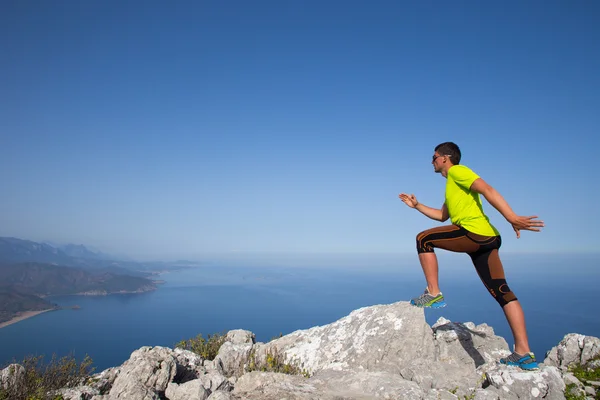 L'uomo pratica il trail running con un paesaggio costiero sullo sfondo — Foto Stock