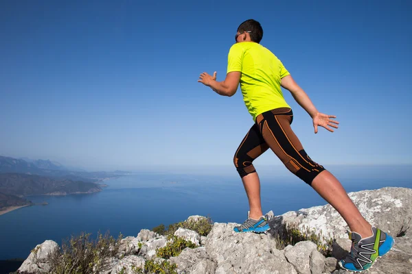 L'uomo pratica il trail running con un paesaggio costiero sullo sfondo — Foto Stock