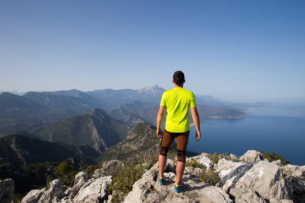 Hombre practicando sendero corriendo con un paisaje costero al fondo — Foto de Stock