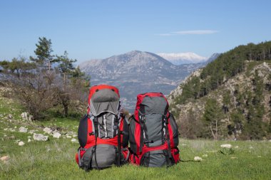 Bir dağın tepesinde duran karlı dağlar arka plan üzerinde sırt çantası.