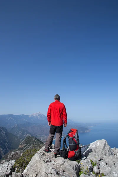 A traveler stands on top of a mountain and looks out to sea. — Stock Photo, Image