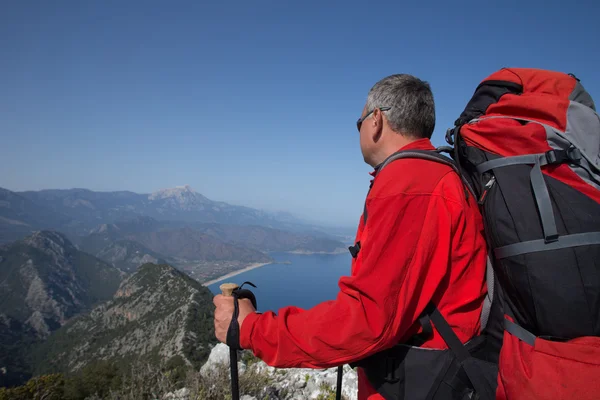 Un viajero se para en la cima de una montaña y mira hacia el mar . — Foto de Stock