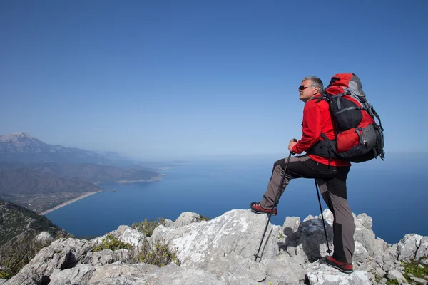 Un viajero se para en la cima de una montaña y mira hacia el mar . —  Fotos de Stock