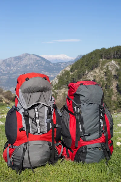 Mochila em pé no topo de uma montanha no fundo de montanhas nevadas . — Fotografia de Stock