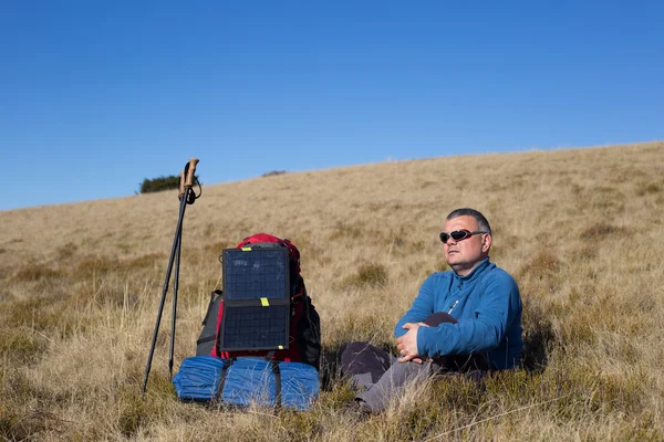 Le panneau solaire fixé à la tente. L'homme assis à côté des frais de téléphone portable du soleil . — Photo