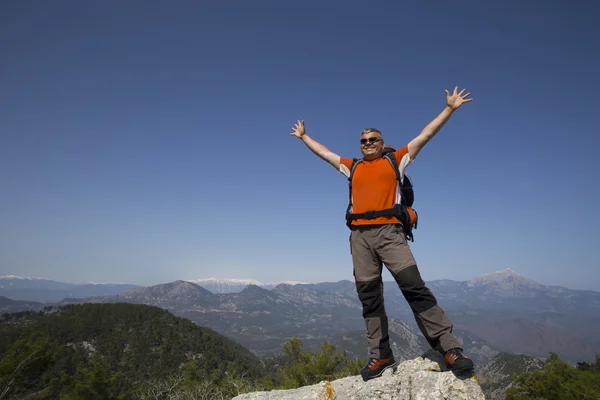 Un viajero se para en la cima de una montaña y mira hacia el mar . — Foto de Stock