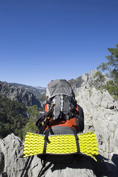 Bir dağın tepesinde duran sırt çantası. — Stok fotoğraf