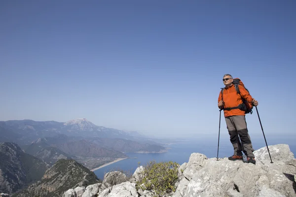 Un viajero se para en la cima de una montaña y mira hacia el mar . — Foto de Stock