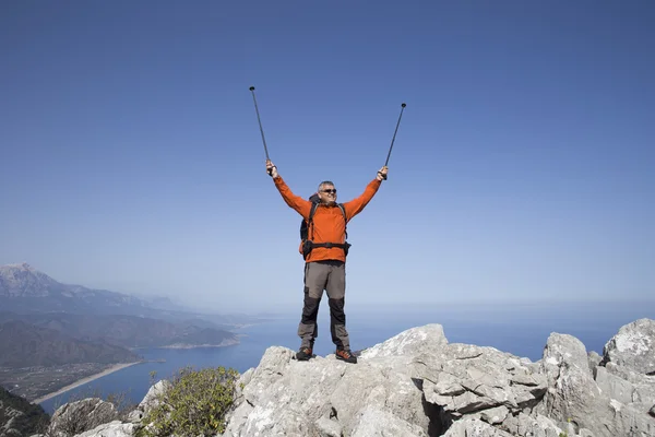 Un viajero se para en la cima de una montaña y mira hacia el mar . — Foto de Stock