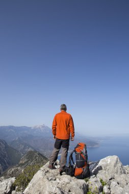 Bir gezgin bir dağın tepesinde duruyor ve denize bakıyor.